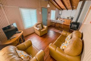 un soggiorno con divani in pelle e una cucina di Cabañas del Río Bueno a Río Bueno