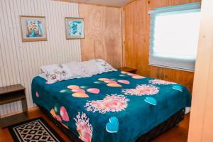 una camera da letto con un letto con una coperta blu con fiori di Cabañas del Río Bueno a Río Bueno