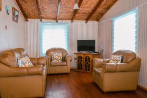 un soggiorno con 2 sedie in pelle e una TV di Cabañas del Río Bueno a Río Bueno