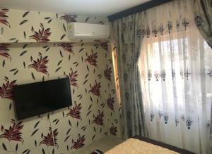 a room with a television on a wall with floral wallpaper at Apartament central in Ploieşti