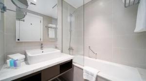 ein weißes Badezimmer mit Waschbecken und Spiegel in der Unterkunft Damac Maison Prive Deluxe Studio with Water Canal View in Dubai