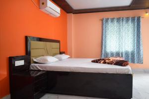 a bed in a room with an orange wall at Pine Apple Resorts in Jalpāiguri