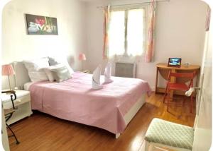 una camera con letto rosa, scrivania e sedia di MaisonTevy - Appart & Studio pro-tourisme a Pontault-Combault