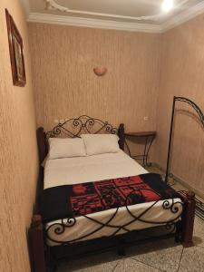 een slaapkamer met een bed met een zwart frame bij Hotel El Golla in Er Rachidia