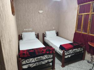 twee bedden in een kleine kamer met een raam bij Hotel El Golla in Er Rachidia