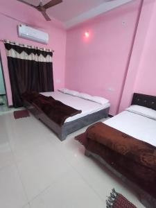 two beds in a room with pink walls at Shikhar guest house 1 in Ujjain