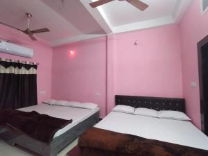 two beds in a room with pink walls at Shikhar guest house 1 in Ujjain