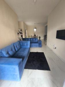 een woonkamer met een blauwe bank en een televisie bij Casa da Hellen in Porto Seguro