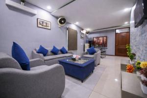 a living room with couches and blue pillows at Private 2BD Apartment Opposite Dha Phase 8 in Lahore