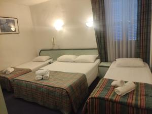 two beds in a hotel room with towels on them at Hôtel de Nevers in Lourdes +30 photos