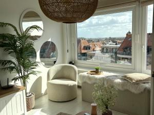een woonkamer met een stoel en een groot raam bij BEACH apartment met directe toegang tot het STRAND ! in Knokke-Heist