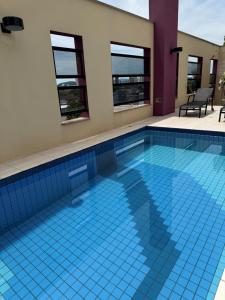 a swimming pool with a blue tile floor and windows at Hotel Germânia in Joinville