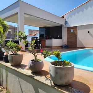 a group of potted plants sitting on a wall near a swimming pool at Casa em São Mateus - Guriri in São Mateus