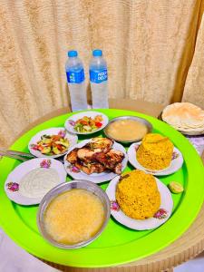 a green table with plates of food and bottles of water at Andy Guest House Pyramids View in Cairo