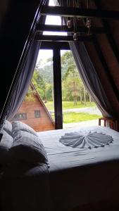 a bed in a room with a large window at Refúgio Bocaina in Bocaina do Sul