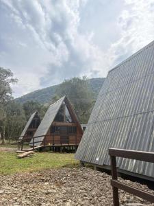 two barns with metal roofs in a field at Refúgio Bocaina in Bocaina do Sul