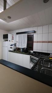 een keuken met witte kasten en een zwart aanrechtblad bij Casa Vargem Pequena in Florianópolis