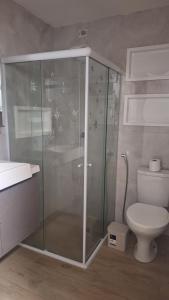 a bathroom with a glass shower and a toilet at Apartamento charme in Praia do Frances