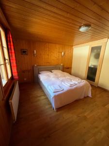 una camera da letto con letto bianco in una camera in legno di L'Auberge de la Combal a La Comballaz
