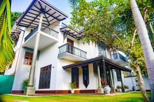 een wit huis met zwarte deuren en bomen bij Elevate Villa Galle in Galle