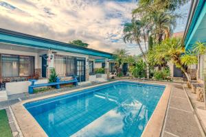ein Swimmingpool vor einem Haus mit Palmen in der Unterkunft Emma Hotel Jaco in Jacó