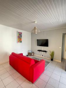 een rode bank in een woonkamer met een flatscreen-tv bij Villa JOSAMY Charmante Villa avec Piscine à Deux Pas de la Mer in Sainte-Luce +24 foto's