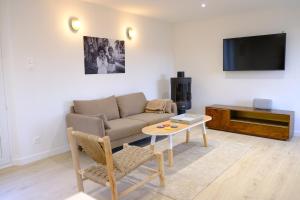 ein Wohnzimmer mit einer Couch, einem Tisch und einem Fernseher in der Unterkunft Les vagues - Sea view house in Saint-Martin-Plage