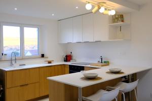 eine Küche mit weißen Schränken und einer weißen Arbeitsplatte in der Unterkunft Les vagues - Sea view house in Saint-Martin-Plage