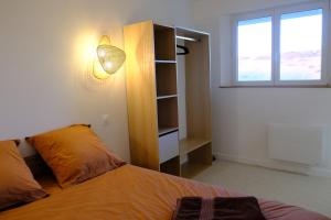 ein Schlafzimmer mit einem Bett und einem Regal und einem Fenster in der Unterkunft Les vagues - Sea view house in Saint-Martin-Plage + 2 Fotos