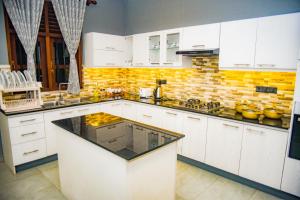 een keuken met witte kasten en een bakstenen muur bij Elevate Villa Galle in Galle