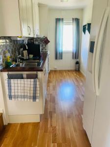 een keuken met een wastafel en een houten vloer bij Cozy Cottage 