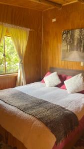 een slaapkamer met een groot bed en een raam bij Cabañas Kuela in Puerto Varas