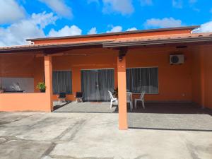 een oranje huis met een terras en een tafel en stoelen bij Casa da Hellen in Porto Seguro