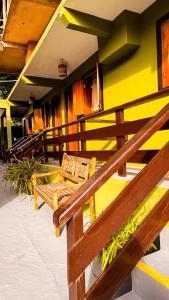 a yellow building with benches on a balcony at Pousada Bosque in Monte Verde