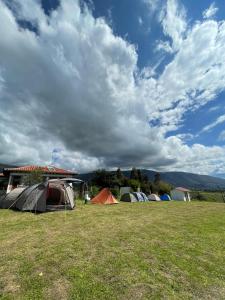 eine Gruppe von Zelten auf einem Feld unter einem wolkigen Himmel in der Unterkunft Zona de Camping El mirador in Villa de Leyva