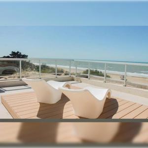 eine Reihe weißer Stühle auf einer Terrasse mit Strand in der Unterkunft Hotel Figueroa Flow Apart in Buenos Aires