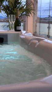 a bottle of wine and glasses in a swimming pool at Mediterranea Apartments Aurora in Assemini
