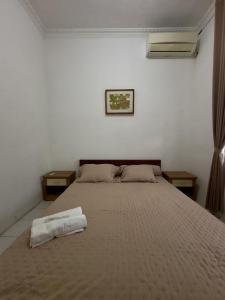 a bedroom with a bed with a towel on it at Omah Putih Jogja in Yogyakarta +8 photos