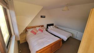 a bedroom with two beds with white sheets and pink pillows at Stornoway Stays in Stornoway