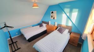 two beds in a room with blue walls at Stornoway Stays in Stornoway