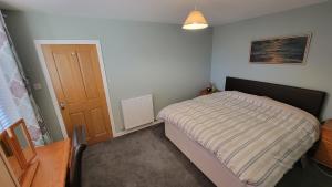 a small bedroom with a bed and a wooden door at Stornoway Stays in Stornoway