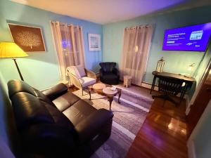 a living room with a couch and a flat screen tv at Gallows Hill Guest House in Salem