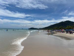 a beach with a bunch of people in the water at Mini Studio Villaggio juquehy in São Sebastião