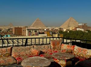 a couch on a balcony with pyramids in the background at Bedouin Camp pyramids view INN in Cairo