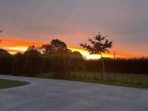 een lege weg met een zonsondergang op de achtergrond bij Self check-in sleepout with bathroom in Te Miro
