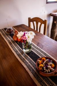 une table en bois avec des fleurs dans un vase et un bol de fleurs dans l'établissement Cabaña Paraíso Cachi, à Cachí