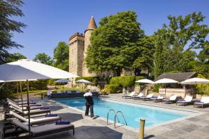 a man standing next to a swimming pool with chairs and umbrellas at Château de Codignat in Lezoux