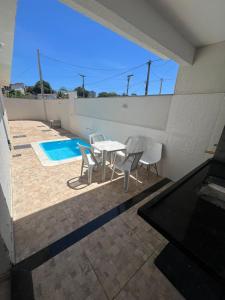 eine Terrasse mit Tisch und Stühlen und ein Swimmingpool in der Unterkunft Casa de Praia Vila do Peró in Cabo Frio