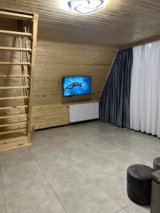 a living room with a tv on a wooden wall at Cottage Godzia in Sadgeri