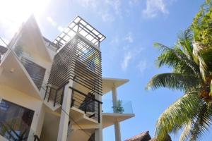 a white building with a balcony and a palm tree at Boracay White Coral Hotel in Boracay